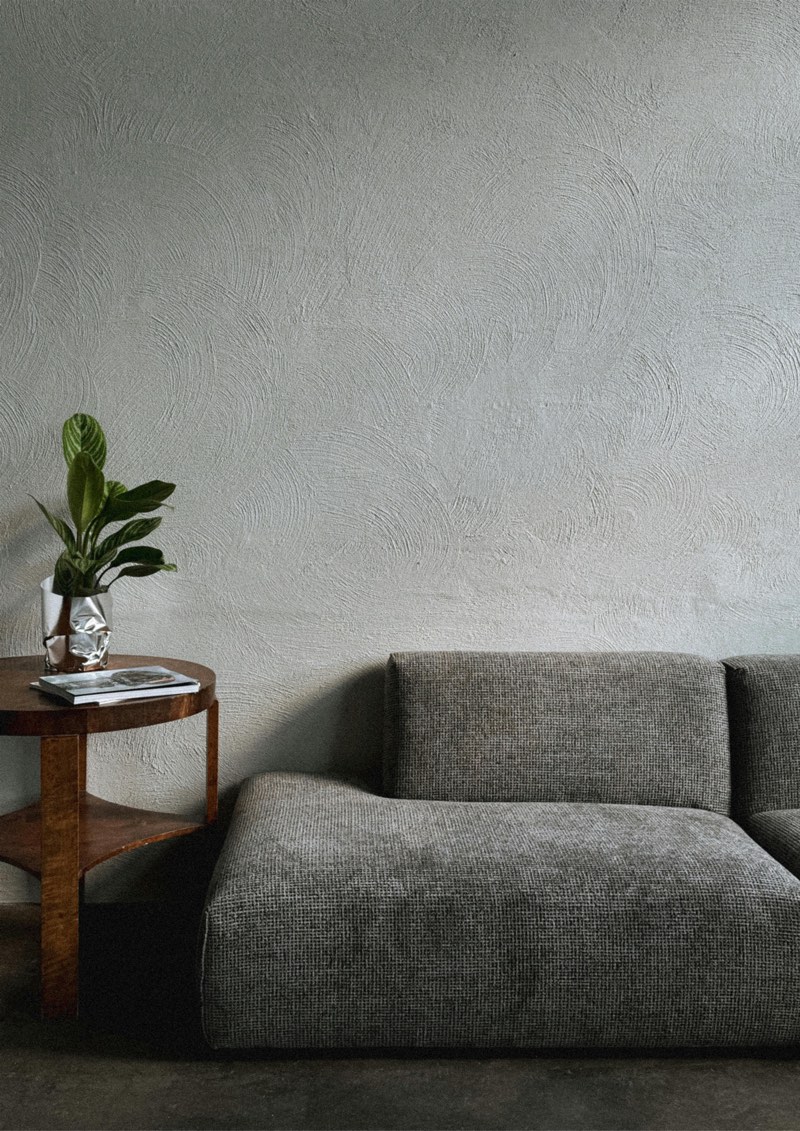 Le tirage encadré sur un mur gris texturé, au-dessus d’un canapé gris