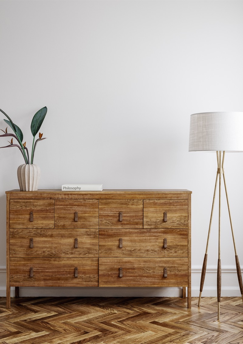 Le tirage encadré sur un mur blanc, au-dessus d’une commode en bois clair, près d’un lampadaire